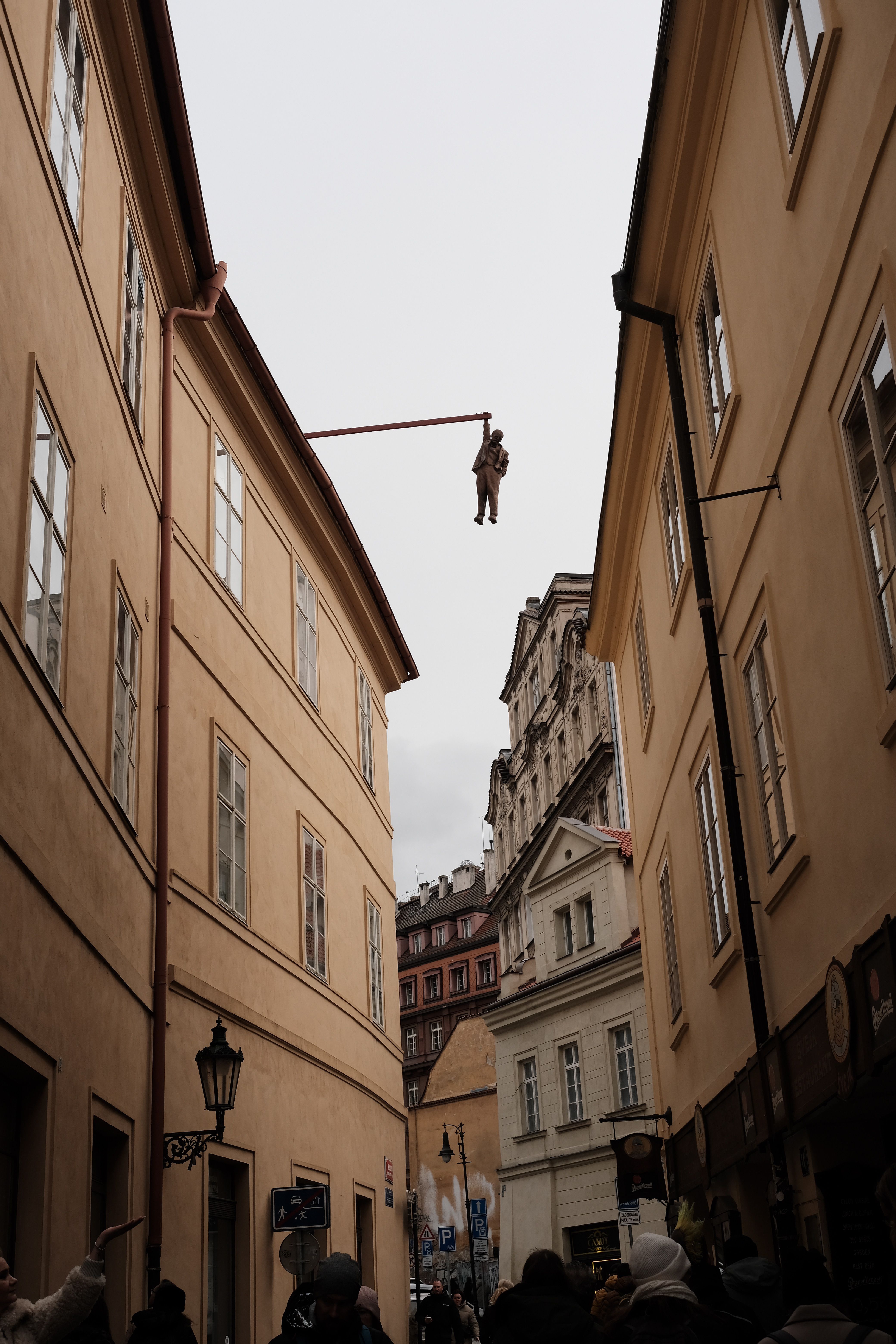 A captivating street view in Prague featuring a unique hanging sculpture among historic buildings.