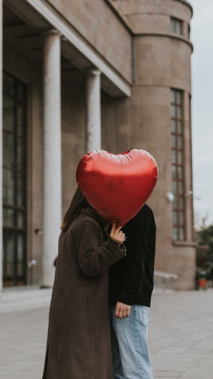 A Couple Holding a Heart Shaped Balloon Standing on a Sidewalk · Free ...