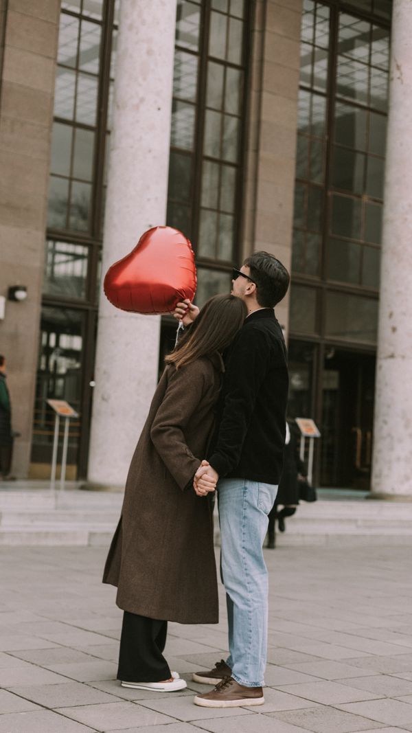 A Couple Holding a Heart Shaped Balloon Standing on a Sidewalk · Free ...
