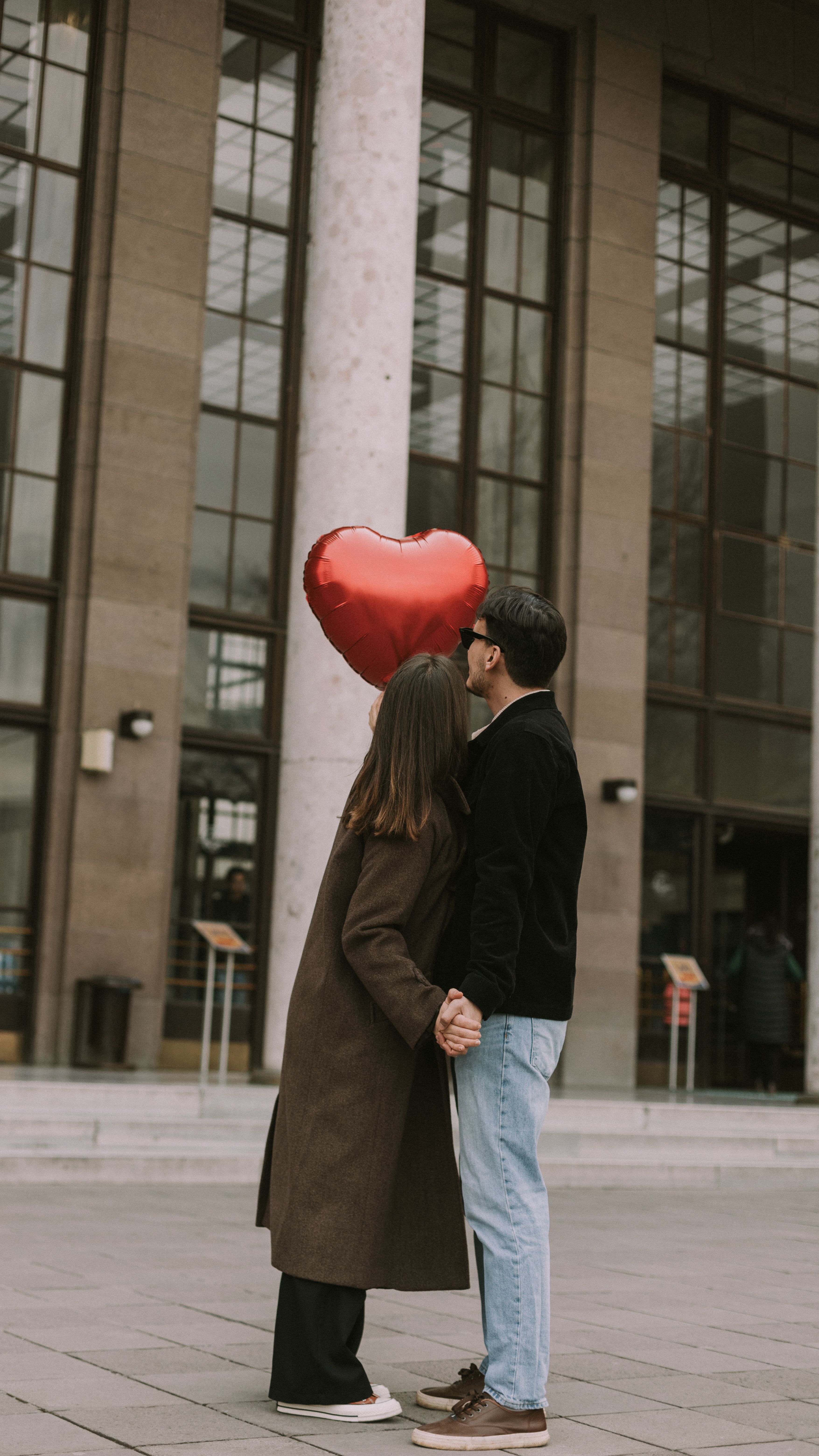 A Couple Holding a Heart Shaped Balloon Standing on a Street · Free ...