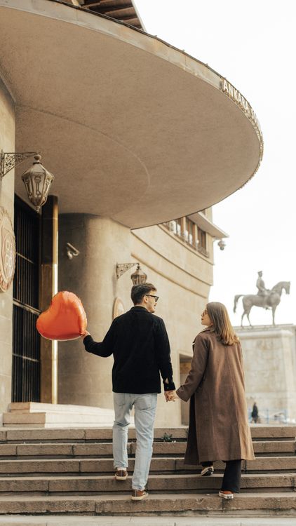 A Couple Holding a Heart Shaped Balloon Walking on Steps in City · Free ...