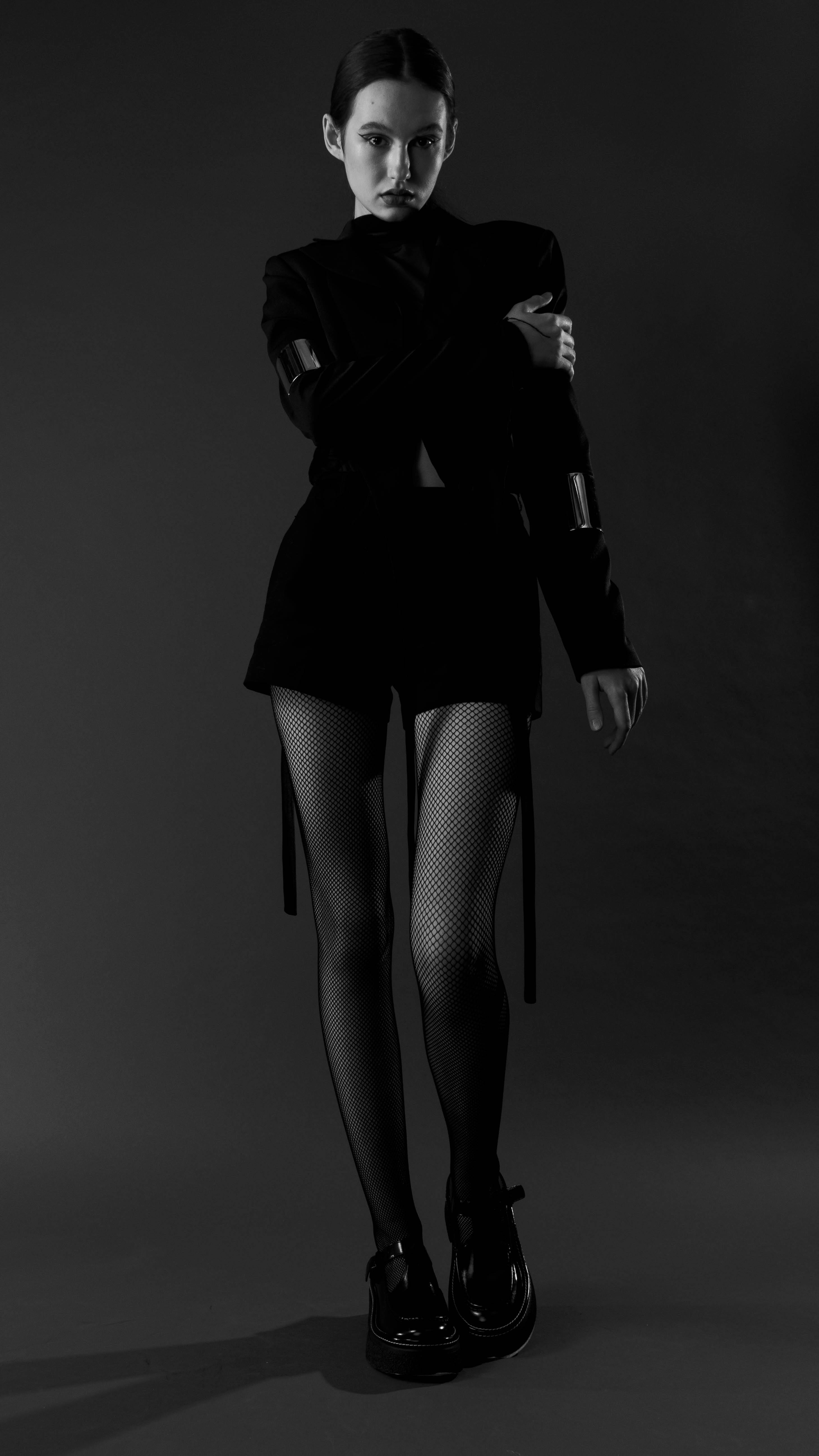 Free Chic fashion portrait featuring a model in a mini dress and tights in a studio setting. Stock Photo