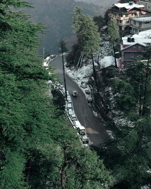 Free A breathtaking aerial view of a snowy road winding through a dense forest in winter.  Stock Photo