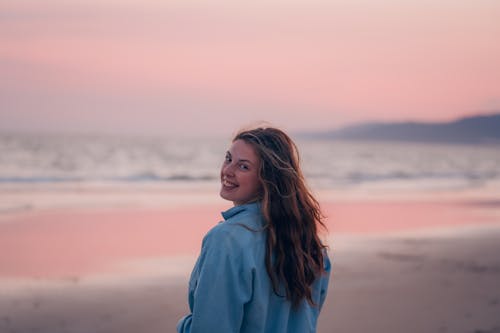 A woman standing on the beach at sunset