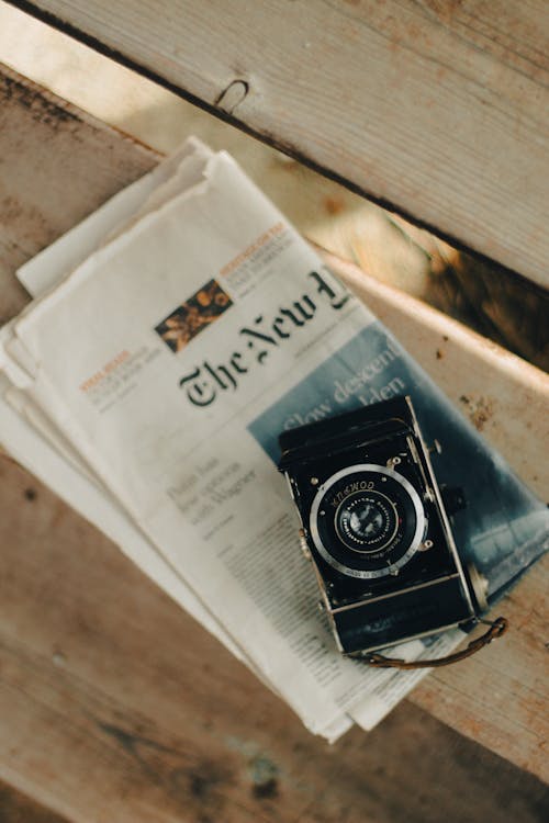 An old camera sitting on top of a newspaper