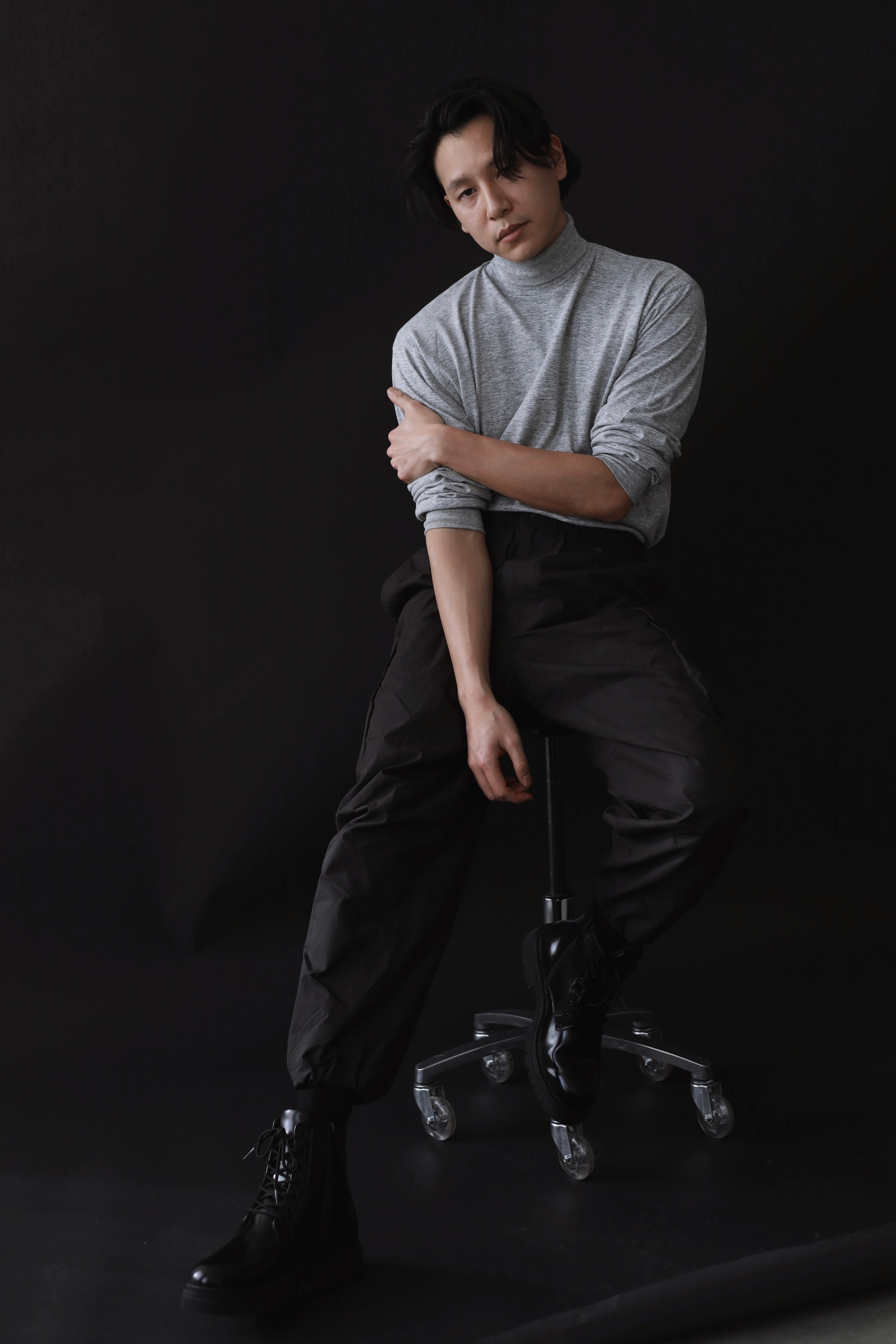 Stylish Asian man in a studio photo shoot seated on a chair. Fashion photography in Berlin.