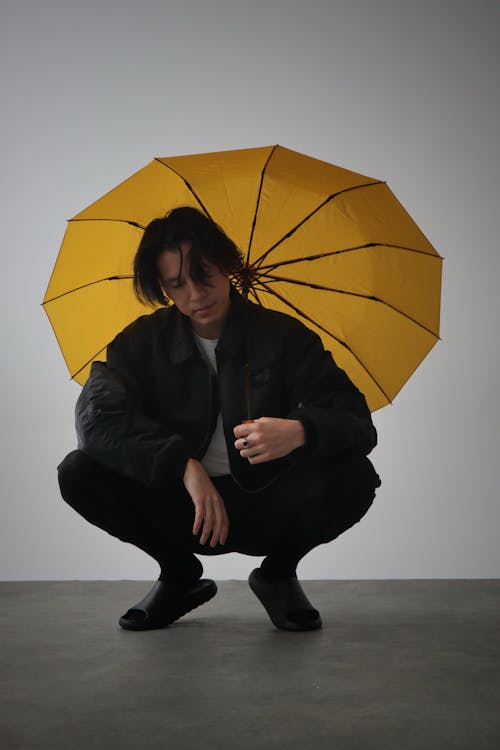 Studio Shot of a Man Holding a Yellow Umbrella 