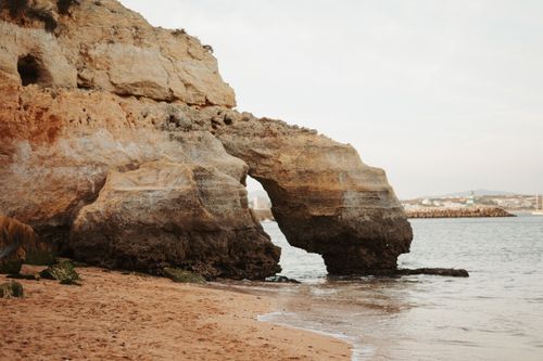 Free Stunning natural arch rock formation on coastal beach shoreline, perfect seascape scene. Stock Photo