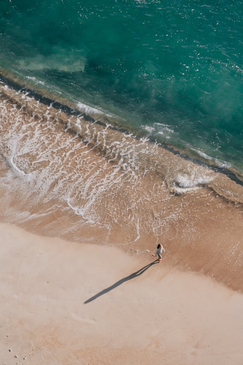 Woman Walking on Sunlit Beach