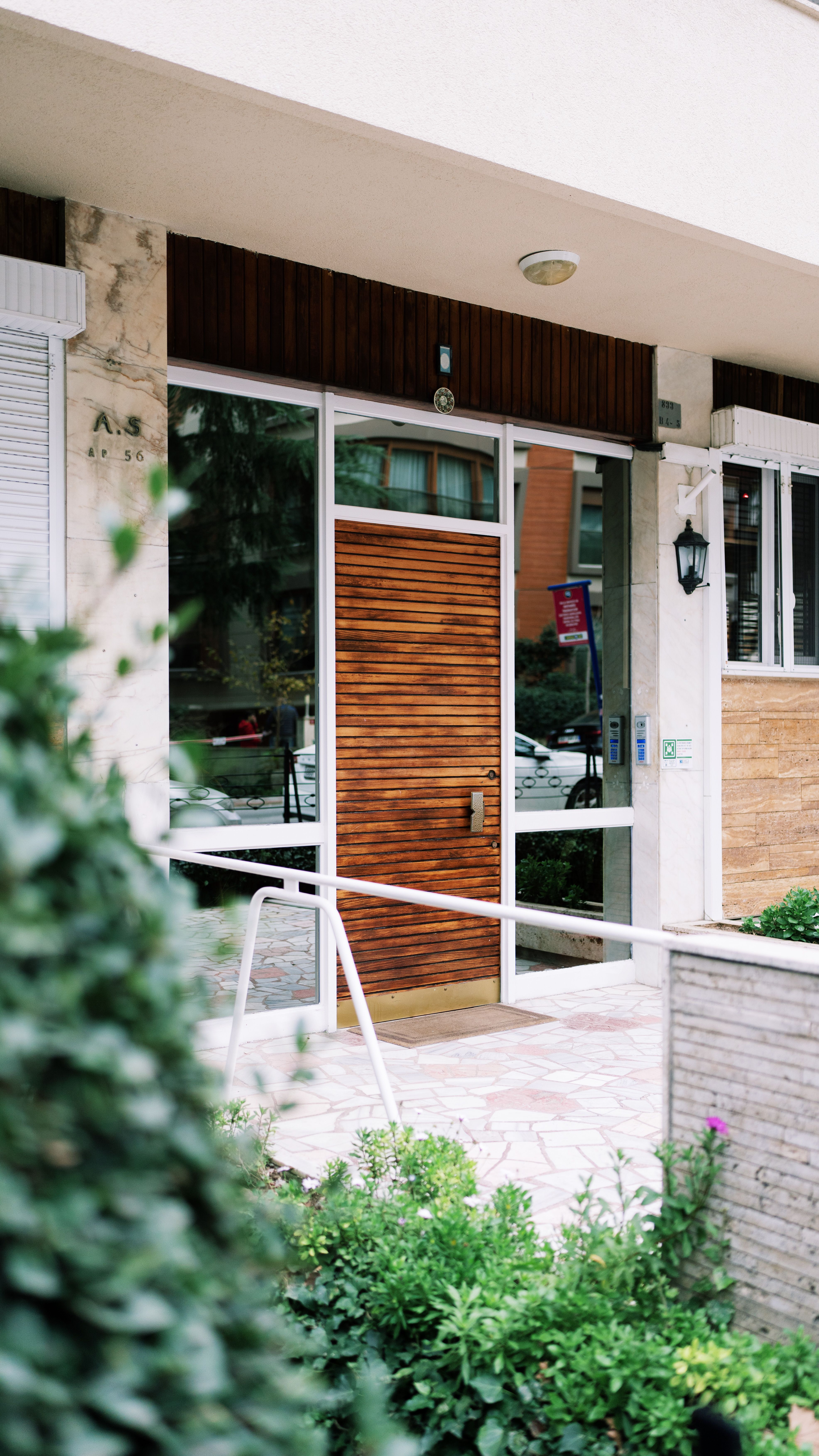 Contemporary urban entrance featuring a sleek wooden door surrounded by greenery in Istanbul.