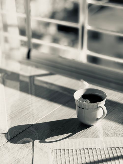 Free A serene black and white image of a coffee cup casting a shadow indoors. Stock Photo