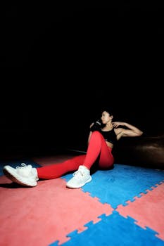 Woman in gym doing exercises wearing red leggings and black sports bra.