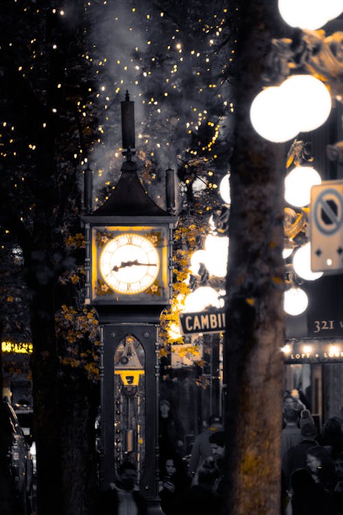 A clock tower is lit up in the middle of a city