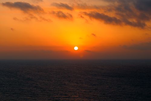 Free Peaceful ocean scene at sunset with a warm, vibrant orange sky and calm sea. Stock Photo