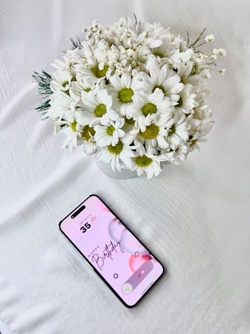 Birthday Message on Smartphone near Vase with Flowers