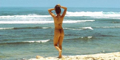 Tourist in a Bikini Walking on the Beach Towards the Sea