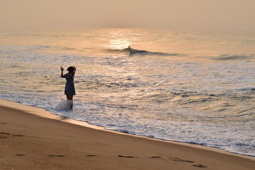 Tourist Standing on the Beach in the Incoming Wave