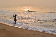 A person enjoys a tranquil moment at the sandy beach of Ouidah, Benin at sunset.