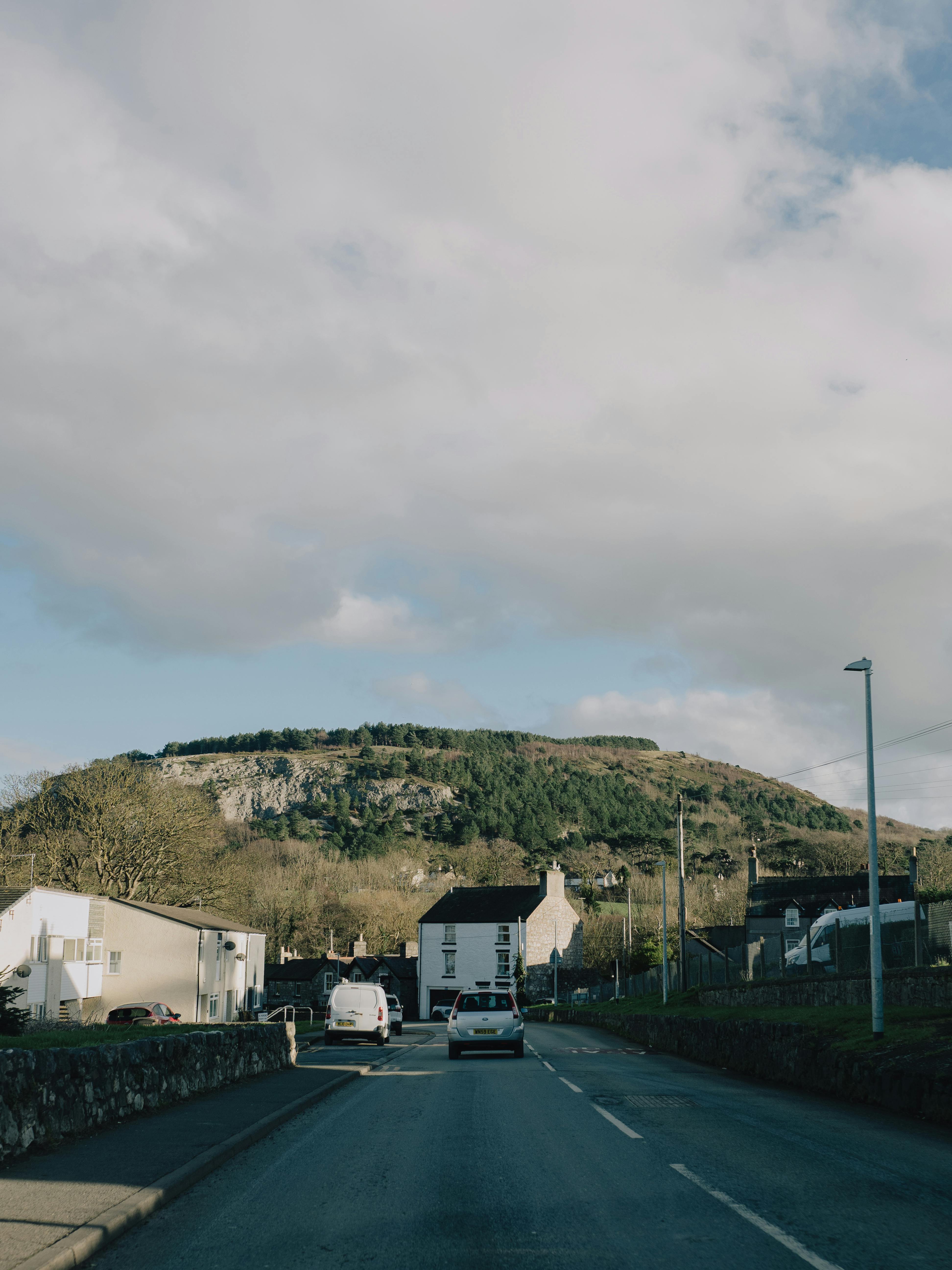 Peaceful drive in Llanddulas, Wales with lush hills and partly cloudy sky.