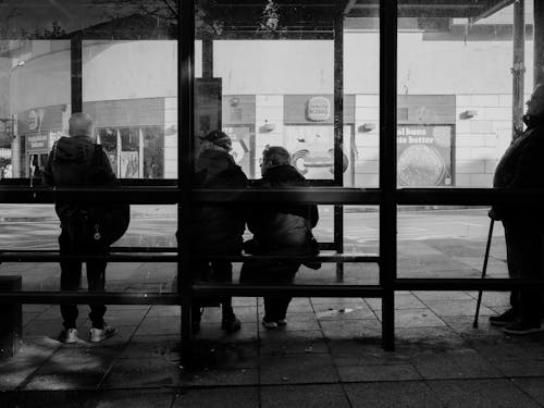 People waiting at a bus stop in black and white