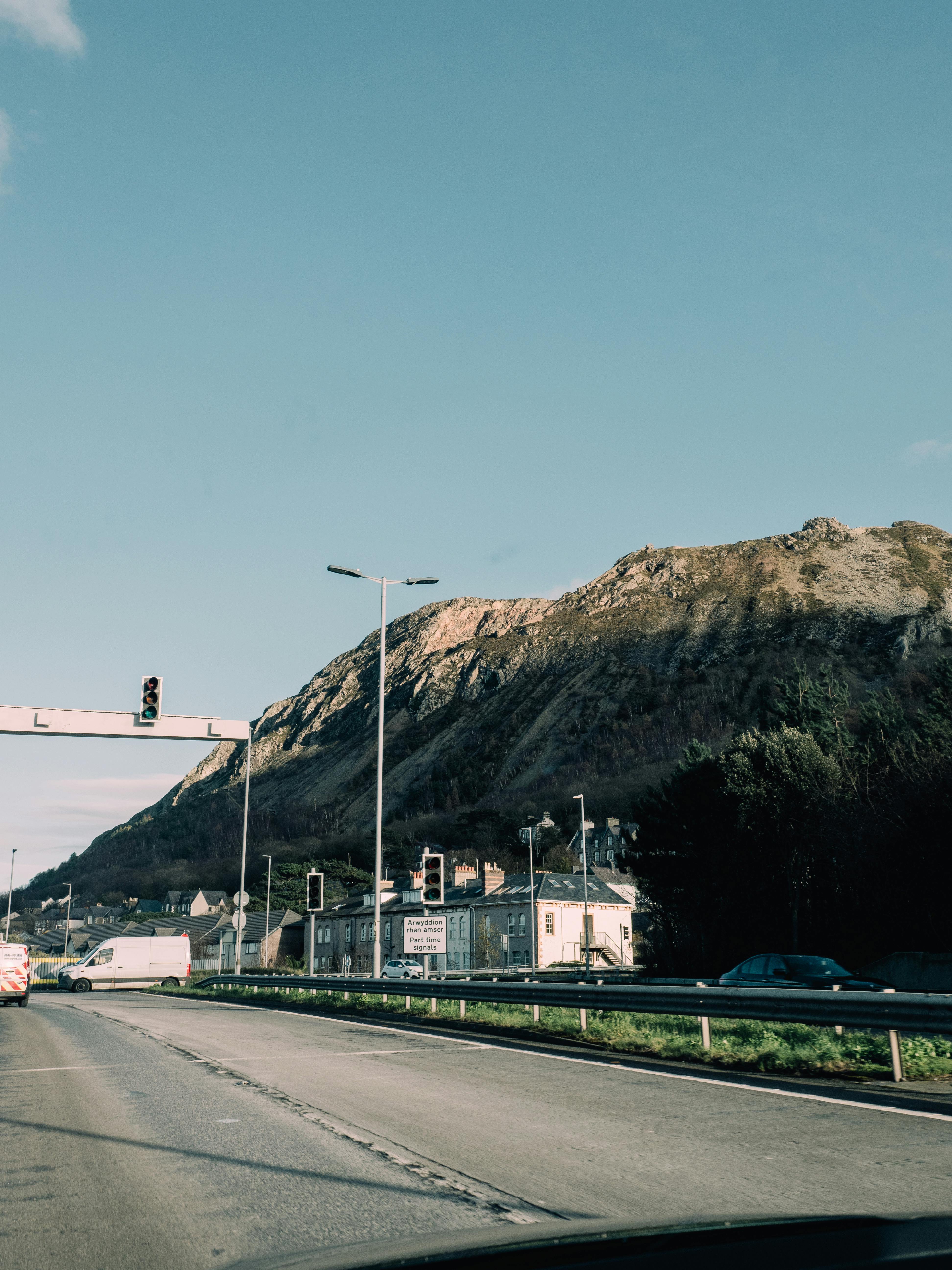 View of a scenic road winding through Penmaenmawr, Wales, with mountains in the background.