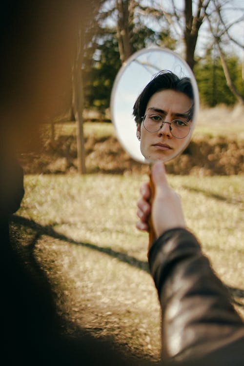 Man Holding a Hand Mirror with his Face on it