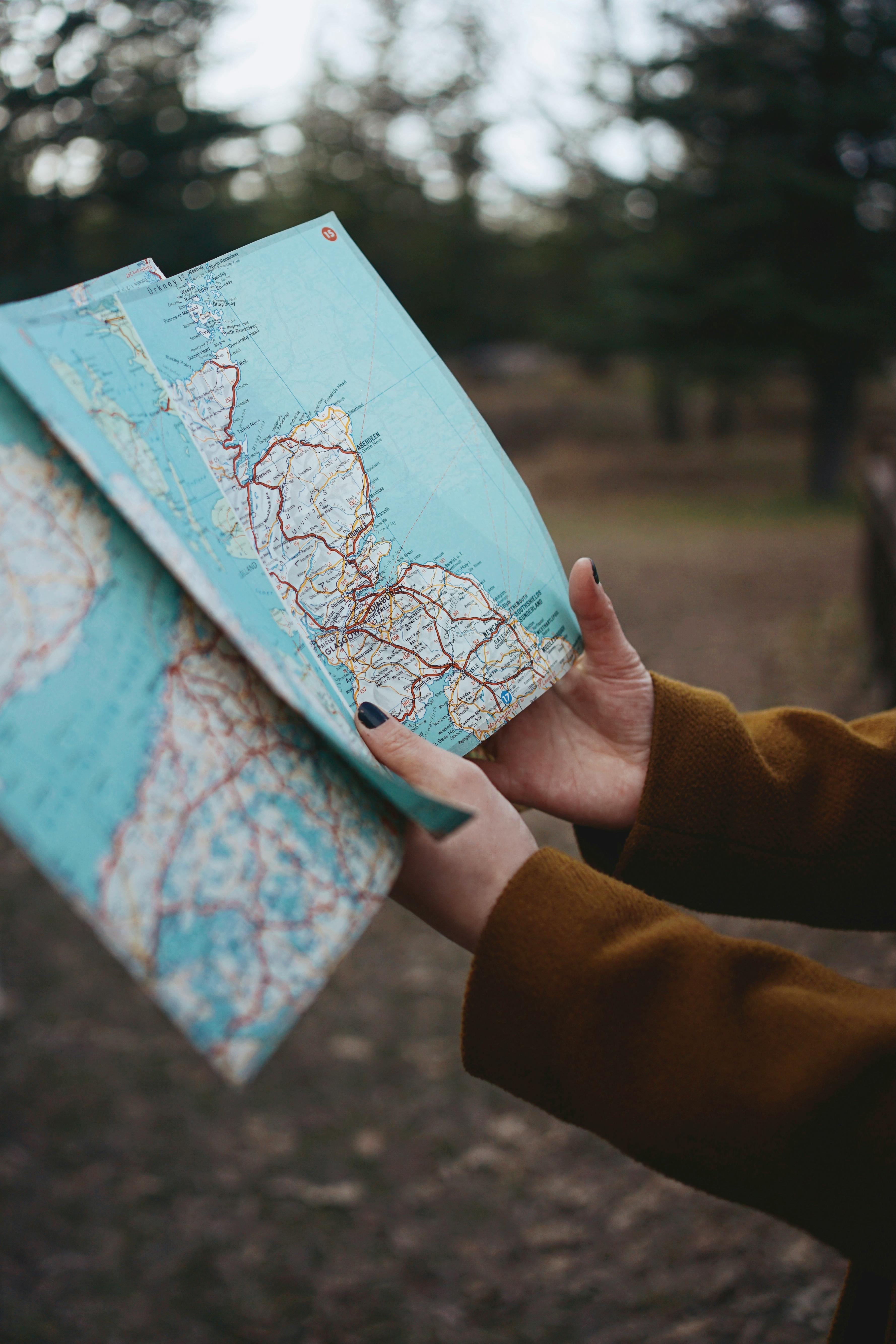 Close-up of hands holding a map outdoors, perfect for travel and navigation themes.