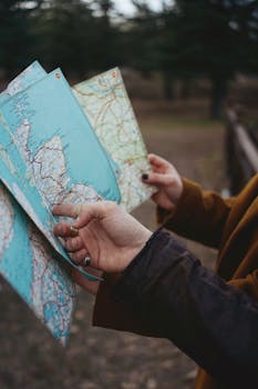 Close-up of hands holding a map, exploring a forest area outdoors.