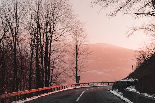 Beautiful sunset view of a snowy road winding through the trees and mountains in Chamonix, France.