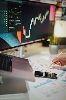 Insightful business analytics with graphs on monitor, papers, and phone calculator.