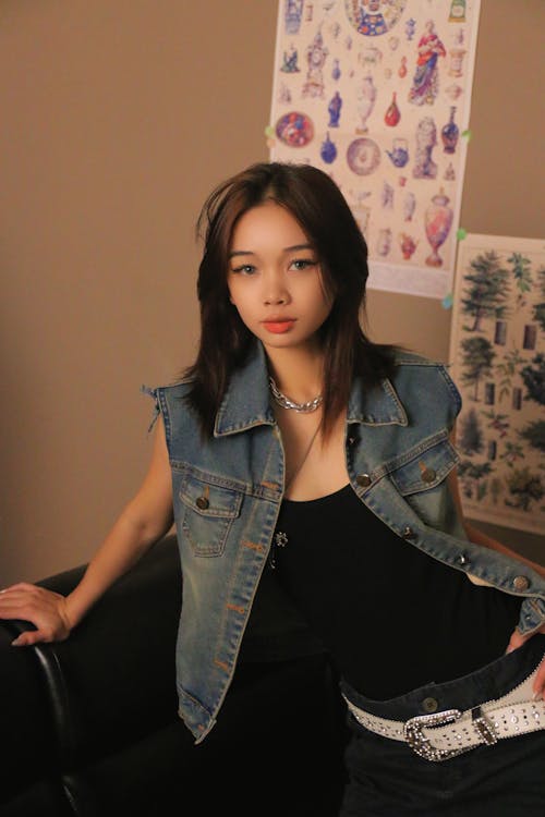 A woman in a denim vest sitting on a couch