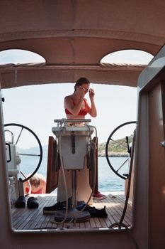 Woman in a red bikini helming a motorboat on a sunny day at sea, enjoying summer vacation.