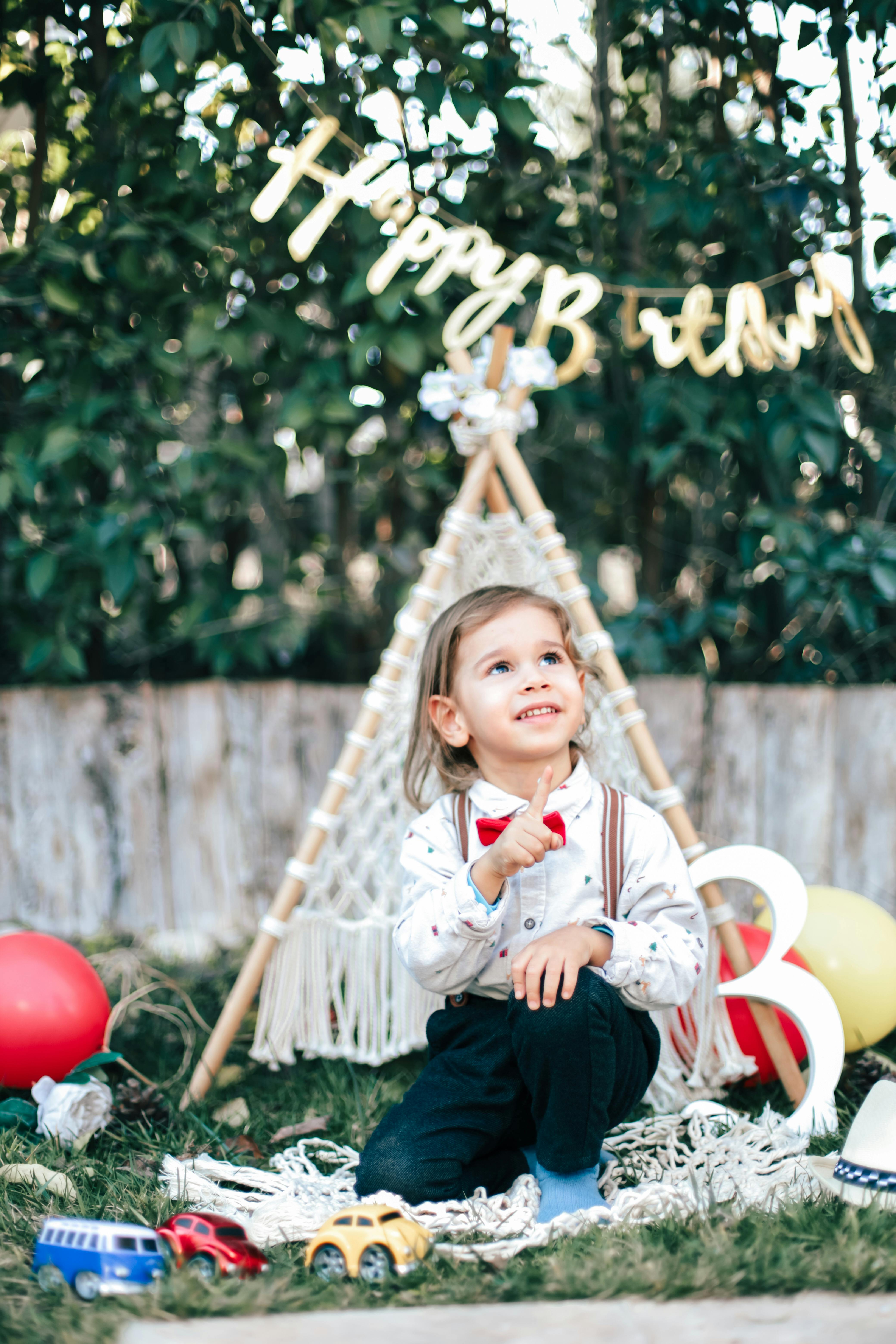Cute child enjoying a colorful birthday party in a backyard with balloons and decorations.