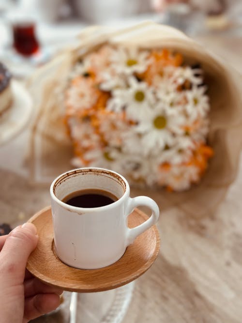 Coffee in Mug over Bouquet of Flowers