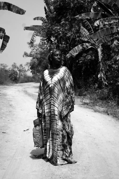 A woman walking down a dirt road with bananas