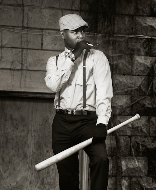 Man in Shirt and Ivy Cap Smoking Cigarette and Holding Baseball Bat