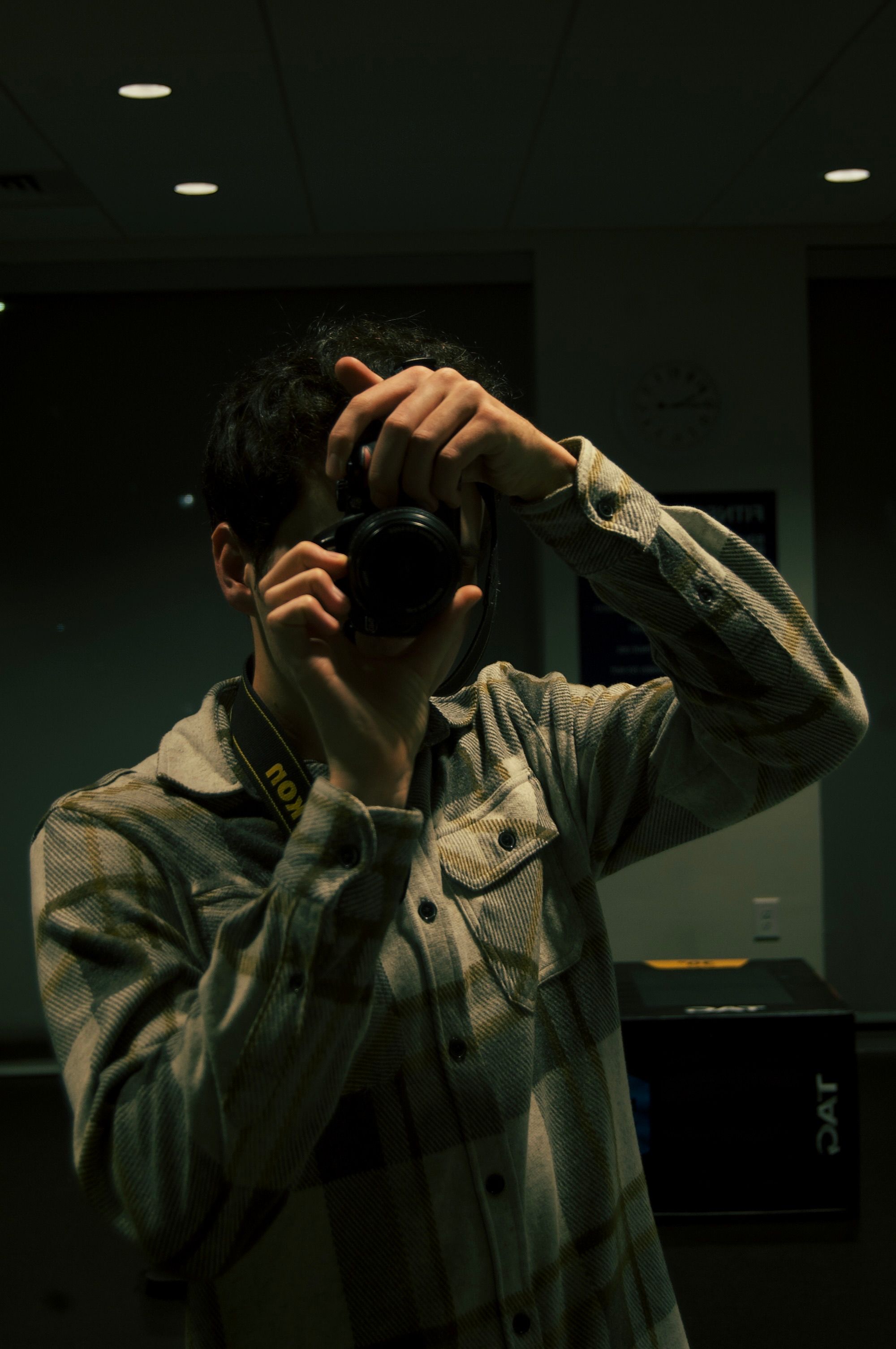 Photographer capturing their reflection in a low-light indoor setting.