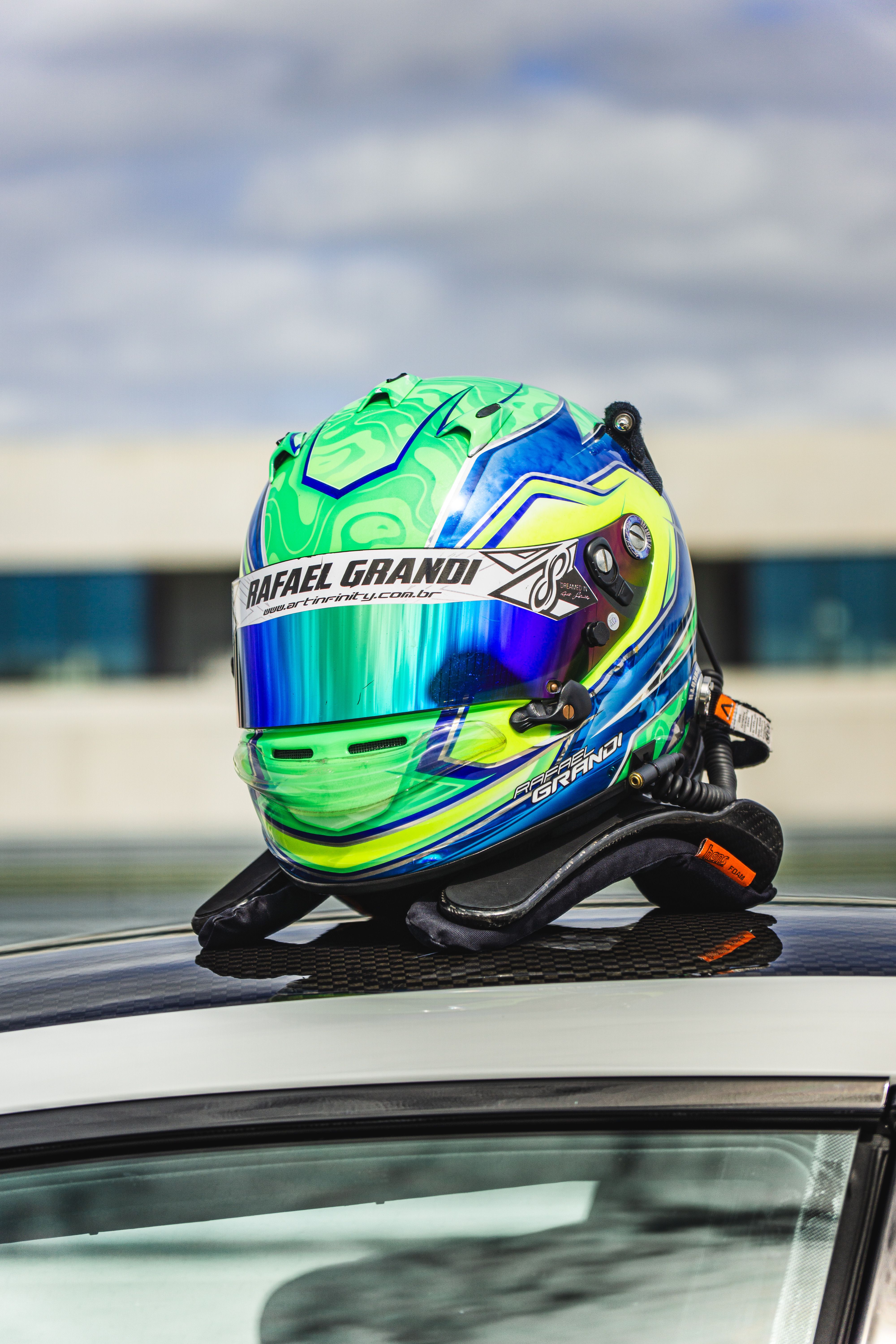 Striking racing helmet sits on a sports car roof, showcasing vibrant colors and design.