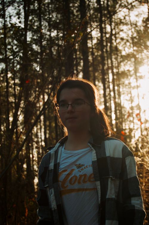 Free Silhouetted woman standing on a forest trail during sunset. Stock Photo
