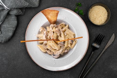 Free Top view of creamy mushroom penne pasta garnished on a stylish plate with cutlery. Stock Photo