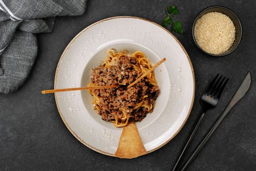 Free Top-down view of a savory spaghetti Bolognese garnished with parmesan cheese on a plate. Stock Photo