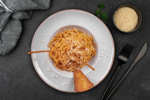 Free Delicious spaghetti coated with Parmesan cheese, garnished with a crispy breadstick on a stylish plate. Stock Photo