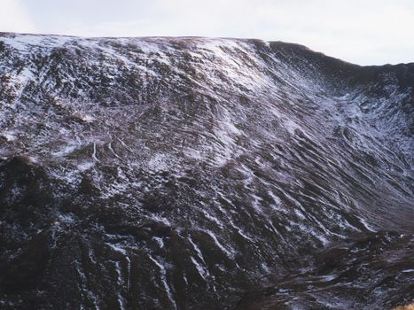 Serene snowcapped mountain landscape with shadows and textures, captured under winter light.