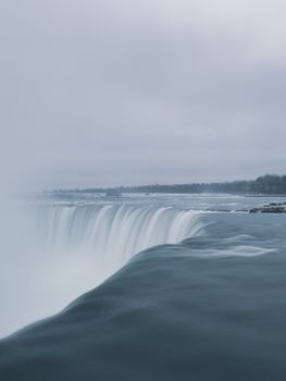 Scenic view of Niagara Falls showcasing its powerful flow against an overcast sky.