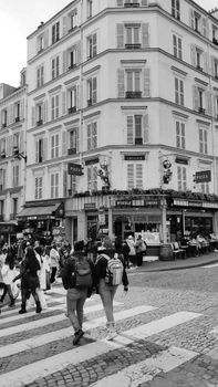 Monochrome view of a Paris street with people walking by a traditional cafe.