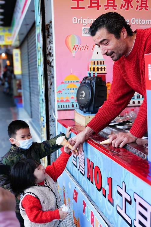 A man is giving a child a toy at a food stand