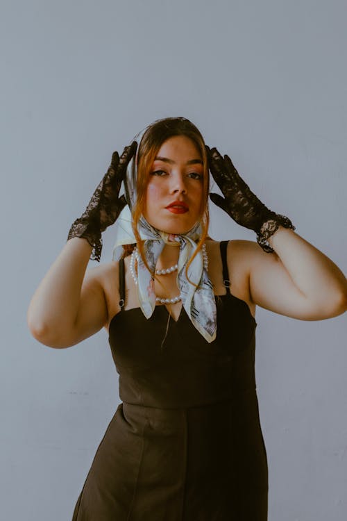 A woman in black dress and gloves holding a scarf