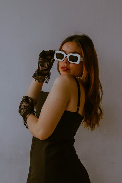 A woman in black dress and sunglasses posing