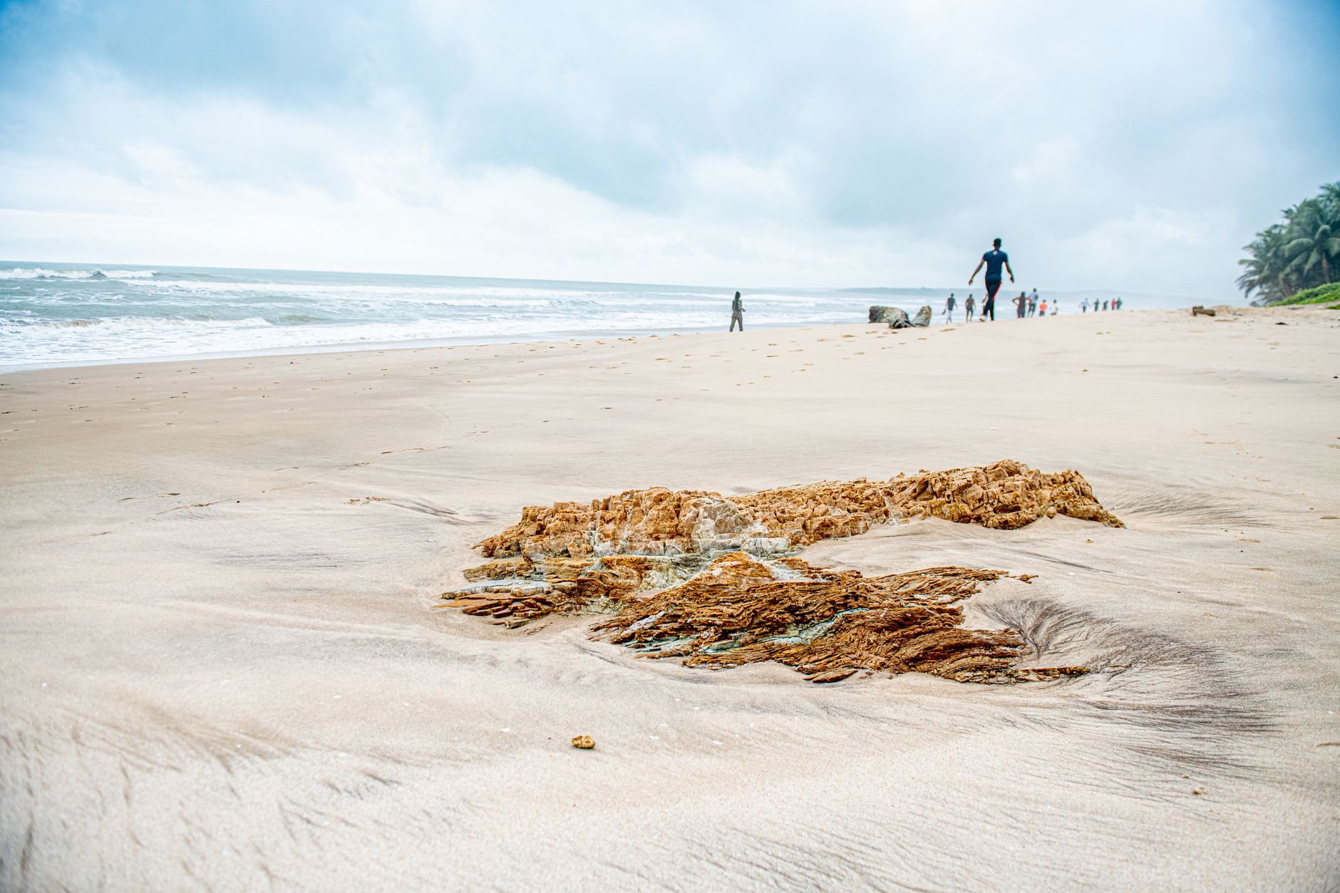 A tranquil beach scene in Accra, Ghana, showcasing sand, ocean, and distant figures.