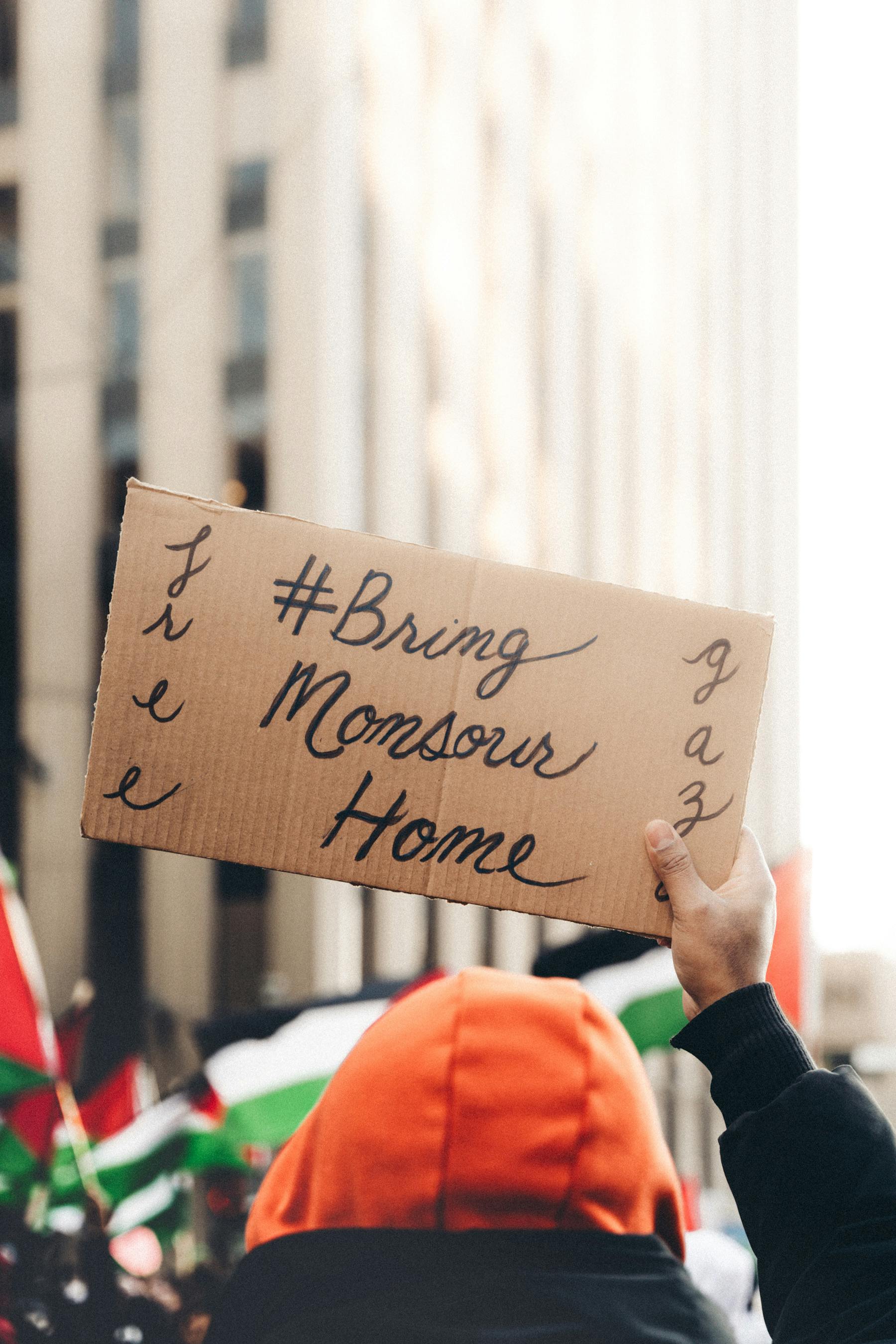 Protest in the city with sign '#BringMonsourHome', advocating justice and freedom.